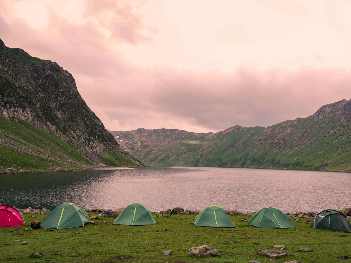 Tents pitched at a lakeside basecamp beneath mountains — family camp