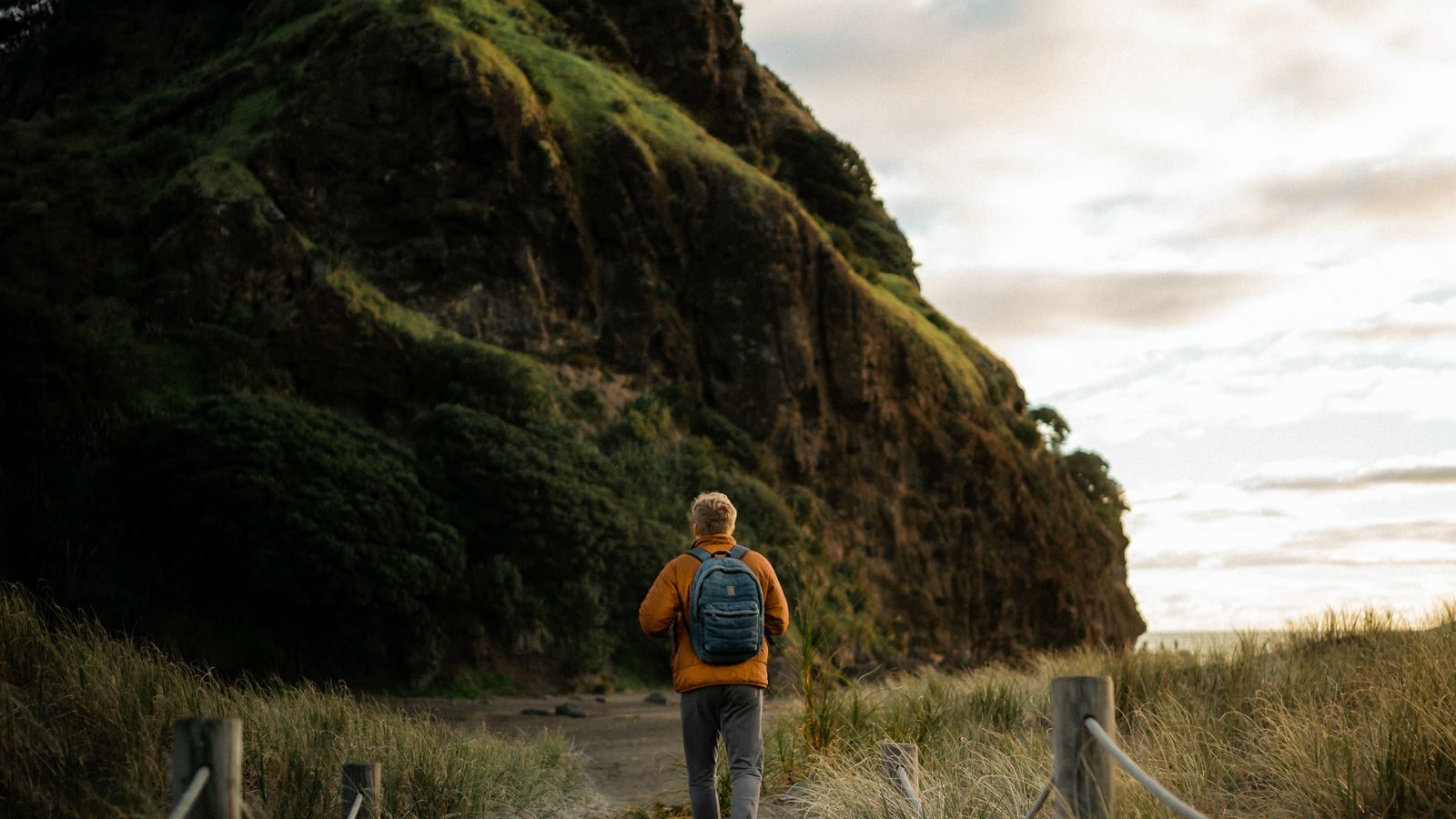 A backpacker walking toward a mountain at sunset on a long trail