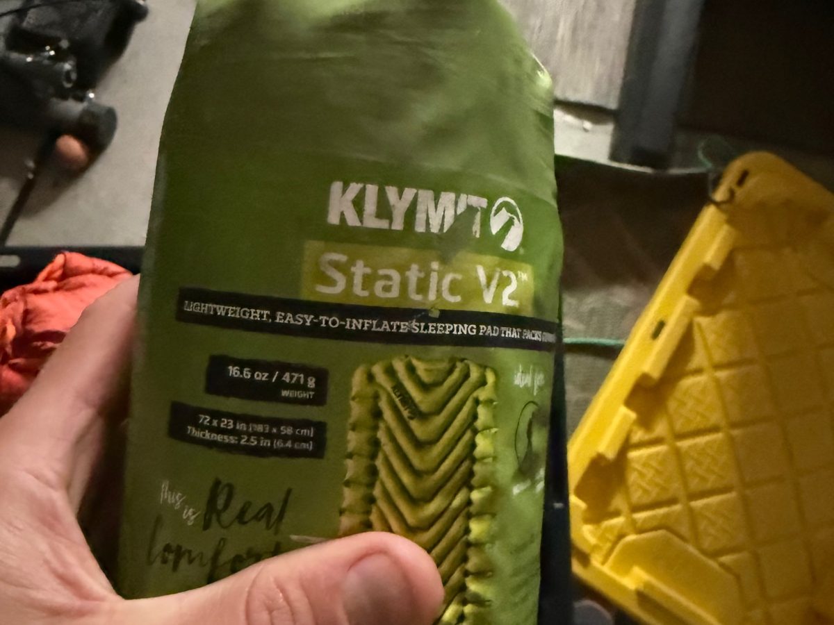 The author's own Klymit Static V2 stuff sack, held in his hand, with its printed specs visible