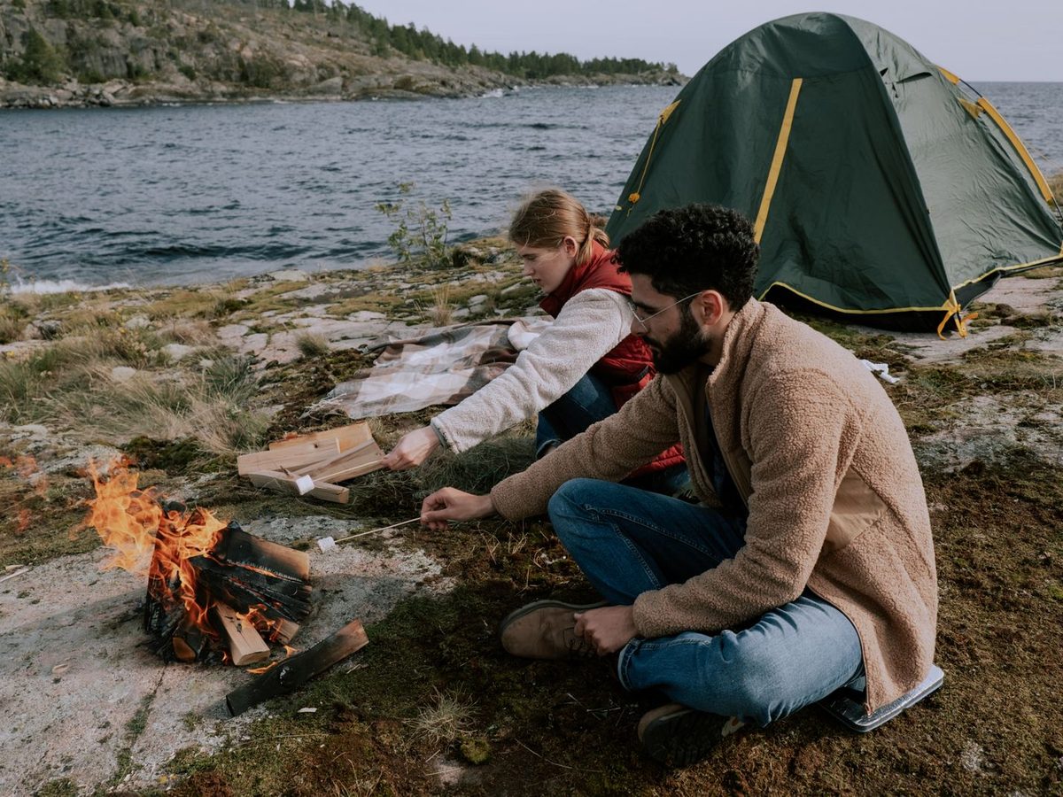 A couple sitting beside a campfire at camp in the evening