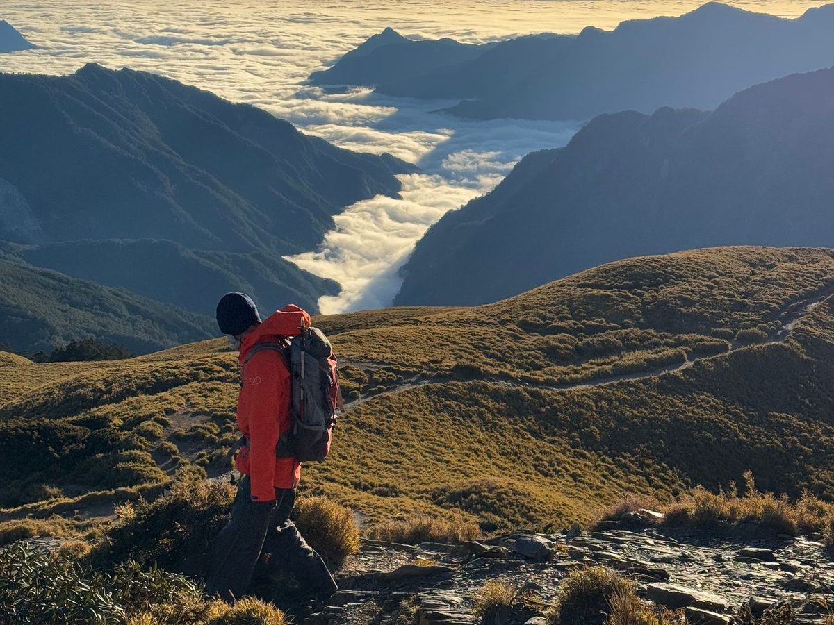A hiker on a mountain trail at sunrise in cold alpine country