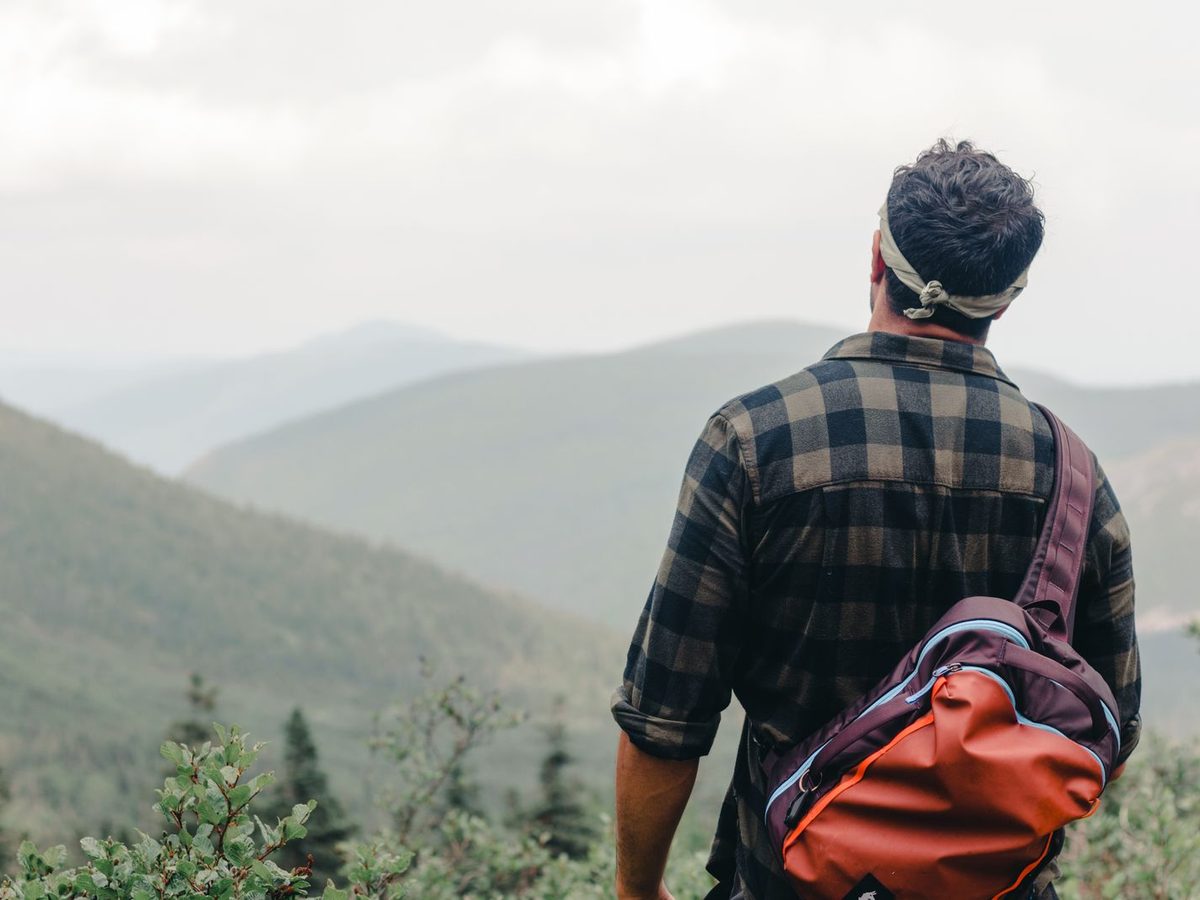 A backpacker facing a mountain view, pack on