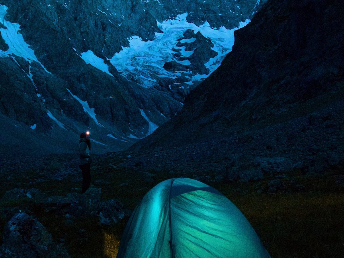 A tent pitched in the mountains at night under a clear sky