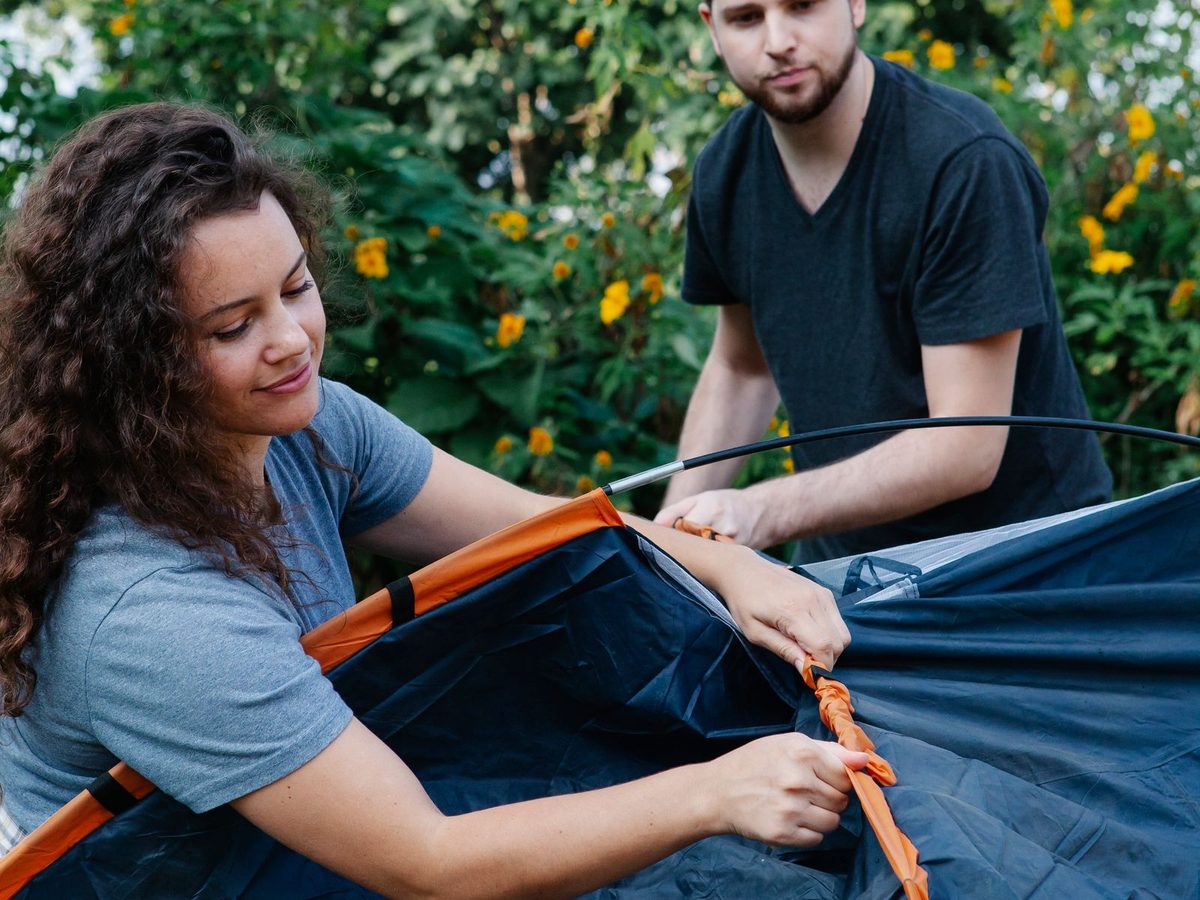 A couple pitching a tent together in a green forest