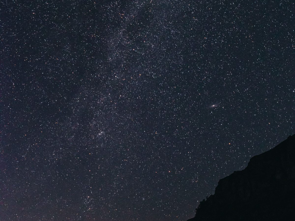 A lit-up tent under the Milky Way on a dark night