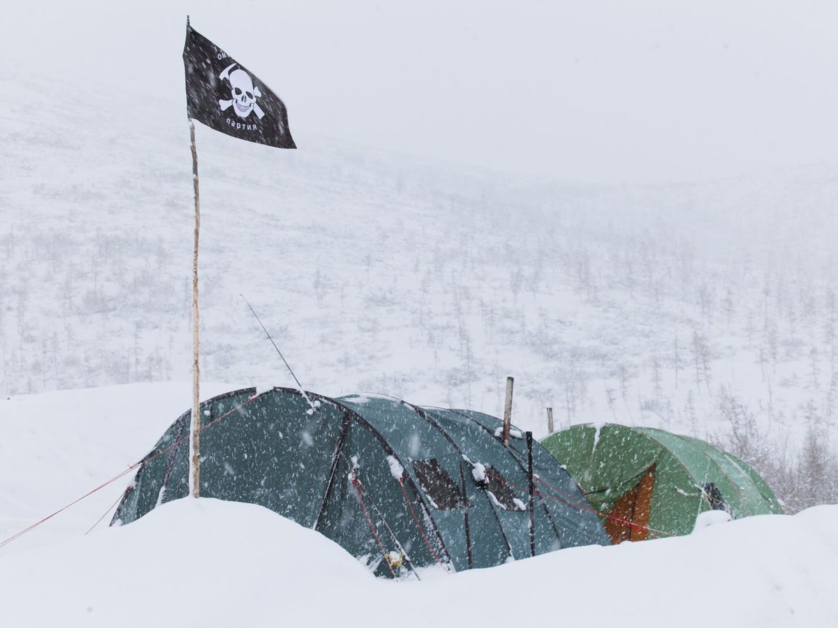 Expedition tents pitched in blowing snow at a high camp