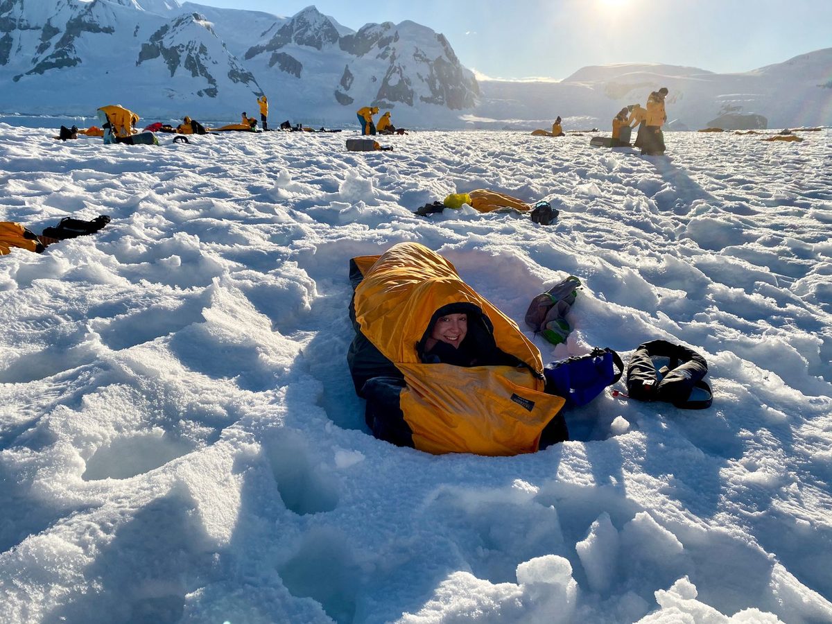 A sleeper lying in a down sleeping bag in the snow