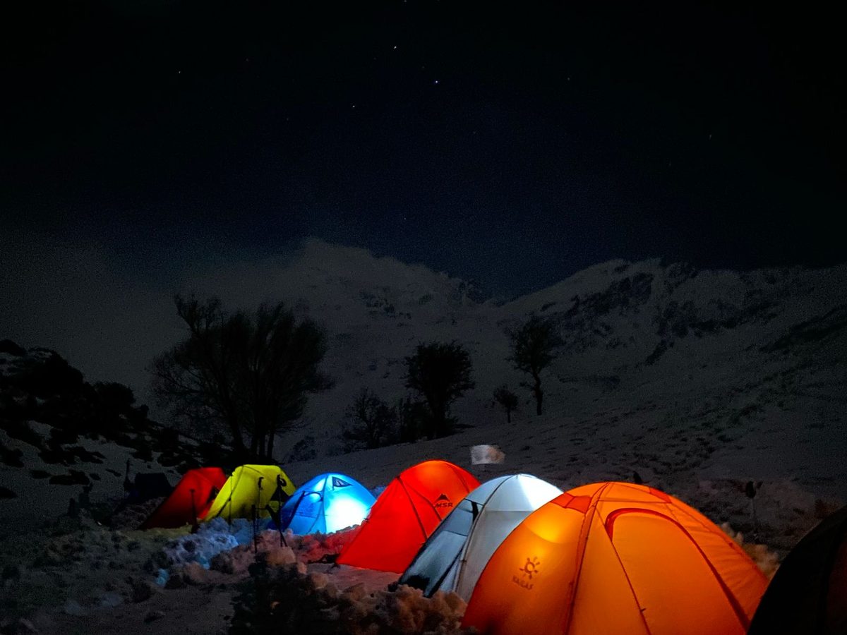 Illuminated tents glowing against a snowy slope at night